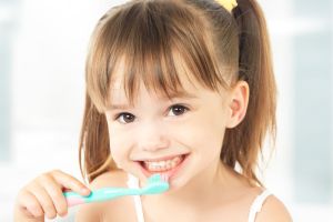 Smiling child brushing her teeth